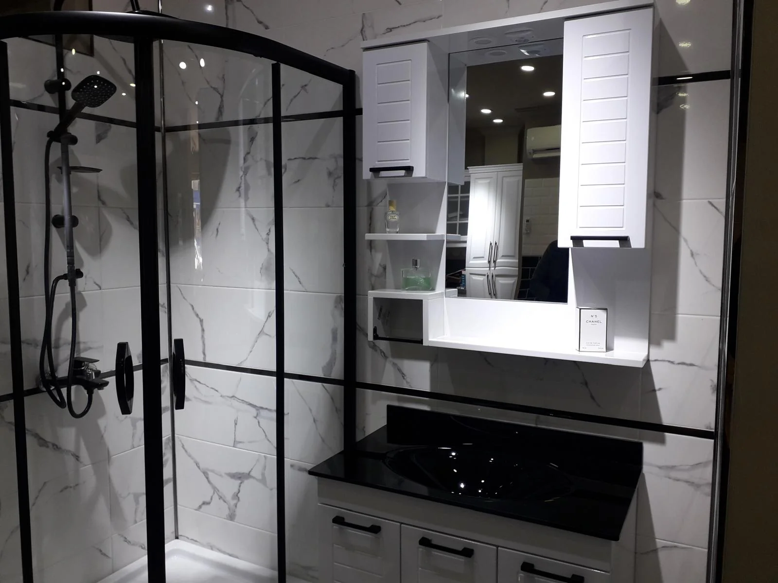 Çetinler uygulamalarından: siyah duşakabinli, beyaz dolaplı ve mermer desenli banyo